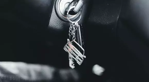 A close up shot of car keys in an ignition, with a silver car keyring.