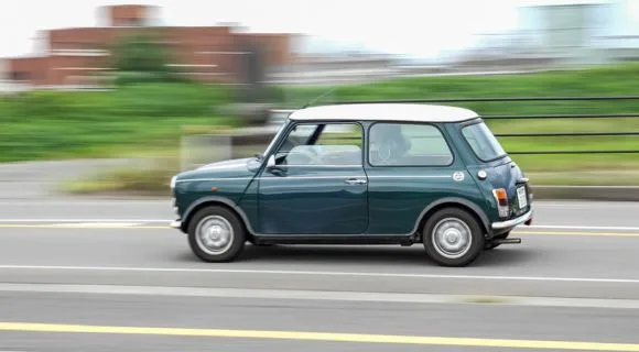 A green mini car driving on the road