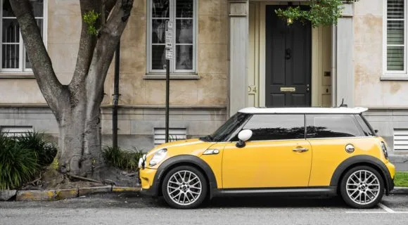 A yellow mini parked in front of a building