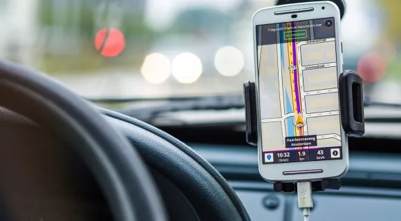 A close-up of an phone in a holder, displaying Google maps for a driver