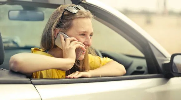 Woman wearing yellow shirt on the phone in a car